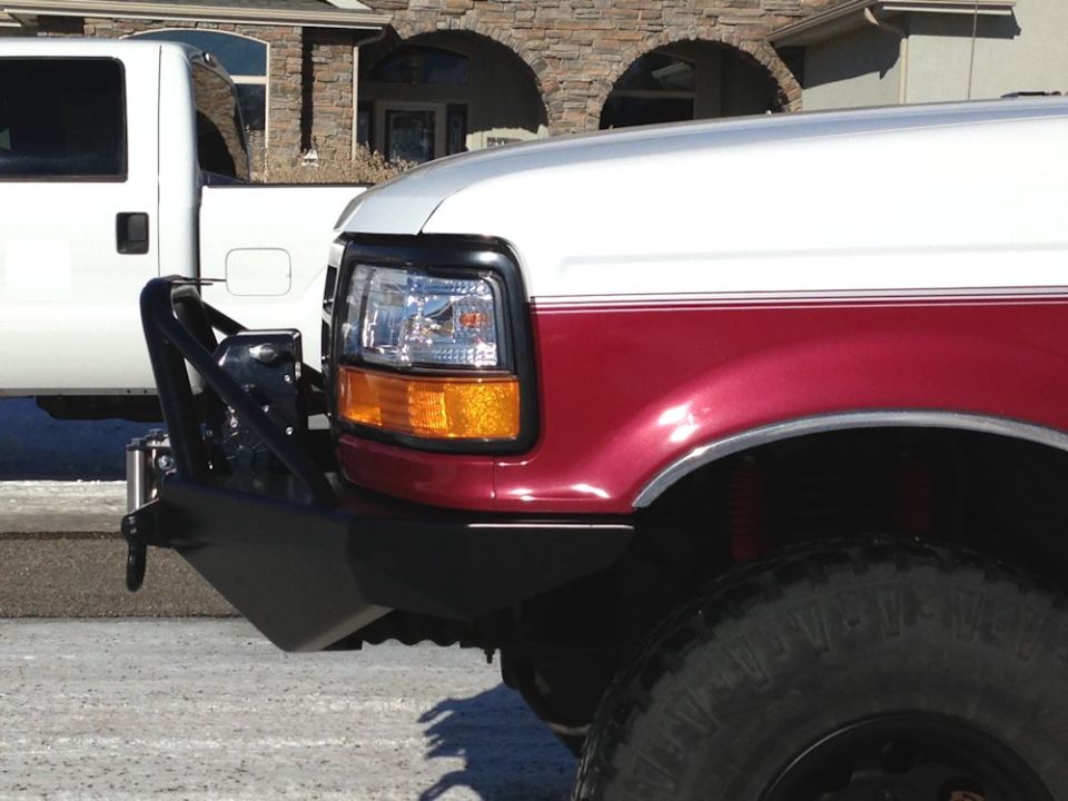 Red and white Ford truck front fender and black aftermarket bumper.