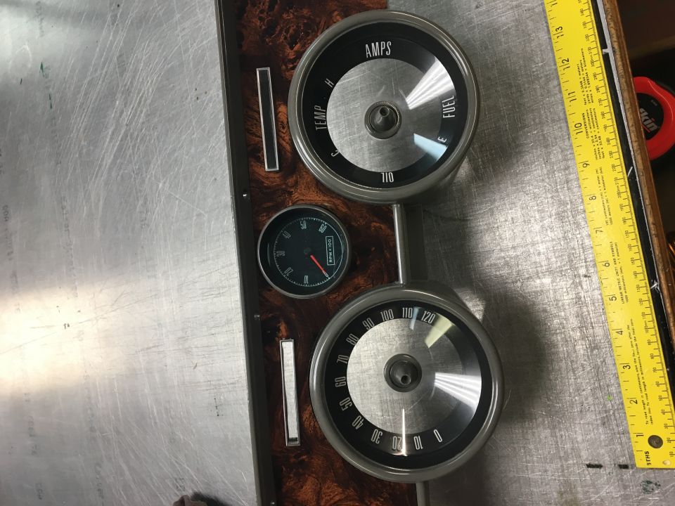 Vintage automotive gauges on wood-grain panel with a ruler