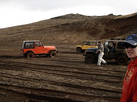 1996 Ford Bronco - Several Jeeps navigate a rough, muddy terrain under an overcast sky.