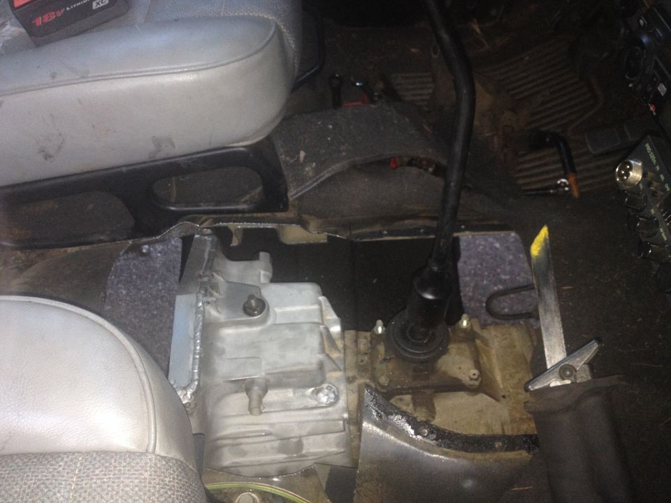 Interior of a vehicle with transmission removed, showing shifter and seat.