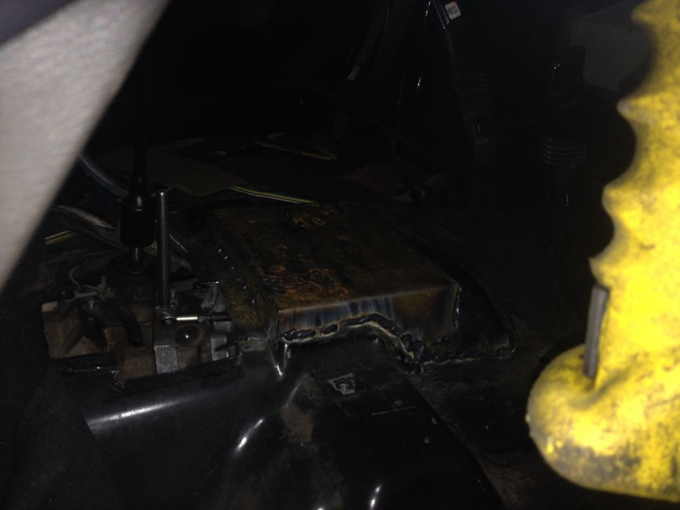 Custom welded metal box around a gear shifter in a vehicle interior.