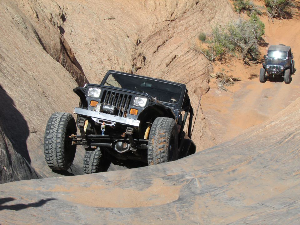 Black Jeep Wrangler YJ driving on a rocky off-road trail.