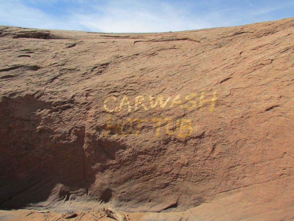 Yellow text spray-painted on a rock face reads "CARWASH" above "HOT TUB".