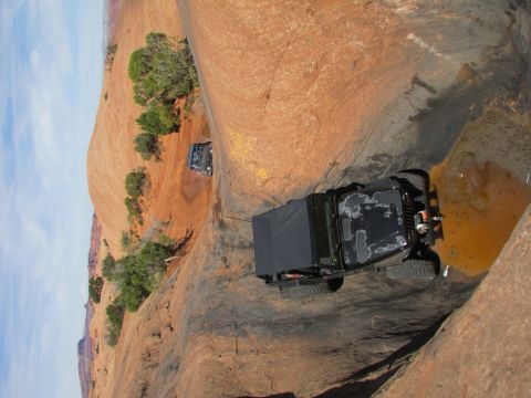 1995 Jeep Wrangler - Two black Jeep Wranglers navigate a narrow, rocky canyon with a small pool of water. The lead Jeep is further up the trail, partially obscu…