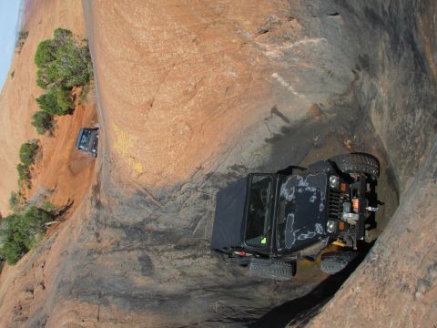 1995 Jeep Wrangler - Two black Jeep Wranglers navigate a narrow, rocky canyon with water on the ground. The Jeep in the foreground is a modified YJ with a soft…