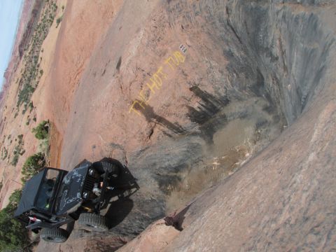 1995 Jeep Wrangler - A black Jeep YJ with a soft top is parked on a steep, rocky incline next to a large, dark, water-filled depression in the rock. Yellow text…