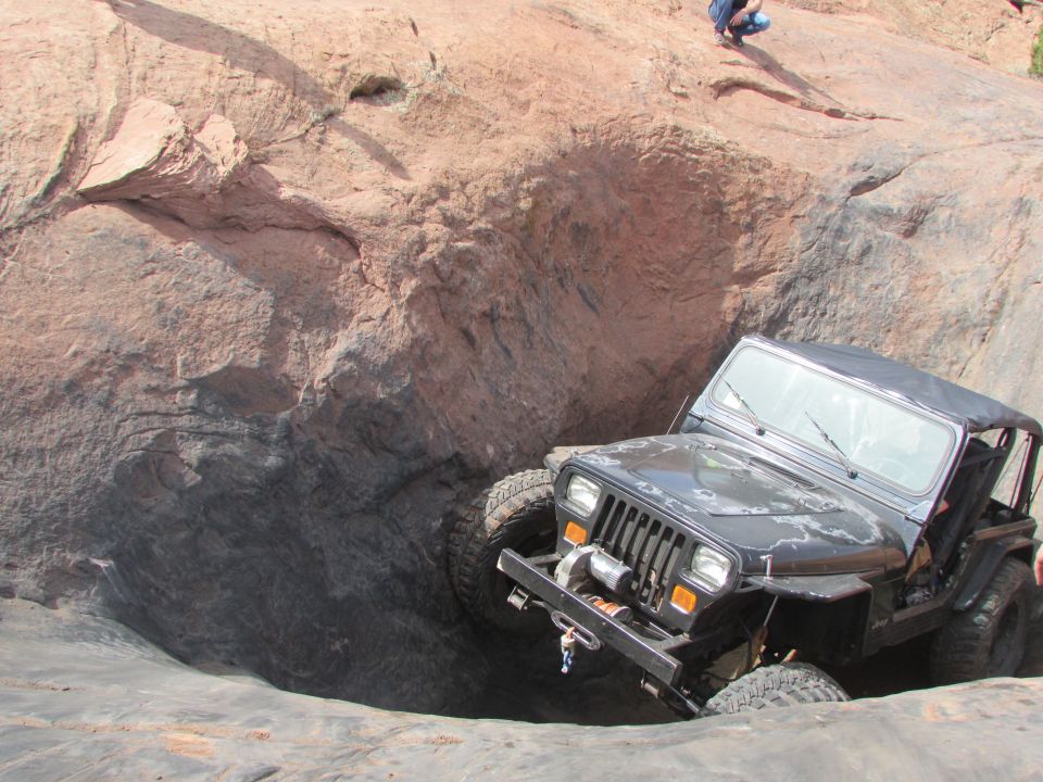 Black Jeep YJ driving down a steep rocky crevice.