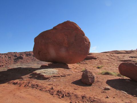 1995 Jeep Wrangler - A large, balanced rock formation sits on a rocky, desert landscape under a clear blue sky.