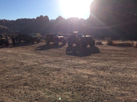 1995 Jeep Wrangler - Several Jeep Wranglers are parked on a dirt lot with a rocky, mountainous landscape in the background under a bright sun.
