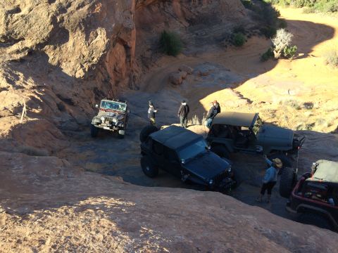 1995 Jeep Wrangler - Several Jeep Wranglers are parked on a rocky, off-road trail with people standing around them. One Jeep in the foreground is black, while o…