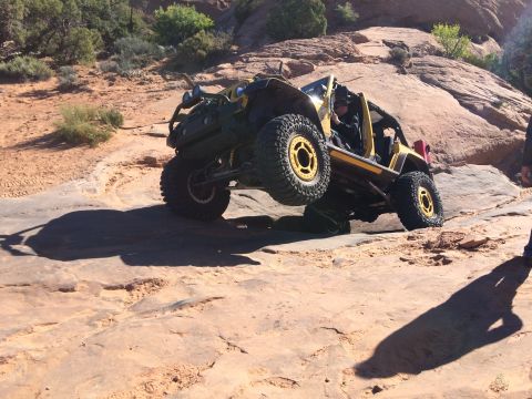1995 Jeep Wrangler - A yellow Jeep YJ is navigating a rocky, off-road trail with one wheel significantly elevated. The vehicle is angled steeply, showcasing its…