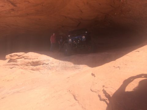 1995 Jeep Wrangler - A blue Jeep Wrangler is parked inside a sandstone cave with two people standing nearby. The vehicle is partially obscured by dust kicked up…