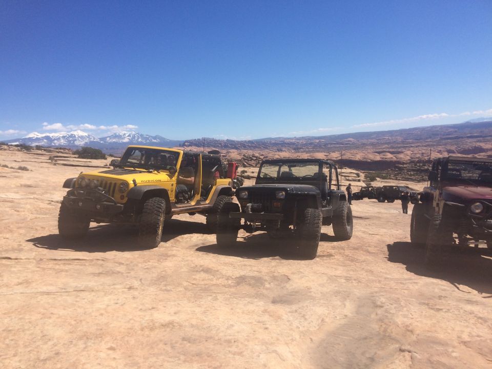 Three off-road Jeeps parked on desert terrain.