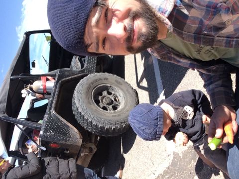 1995 Jeep Wrangler - A man takes a selfie with a modified Jeep YJ in the background. A baby in a blue beanie is sitting next to the Jeep, and the man is holding…