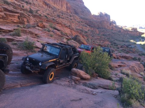 1995 Jeep Wrangler - A black Jeep Wrangler Rubicon with the top removed is navigating a rocky, off-road trail. A red Jeep is visible behind it, also on the trai…