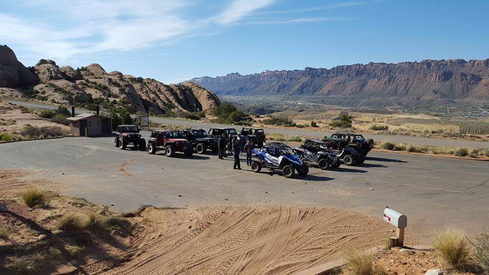 Off-road vehicles parked in a desert landscape with mountains.