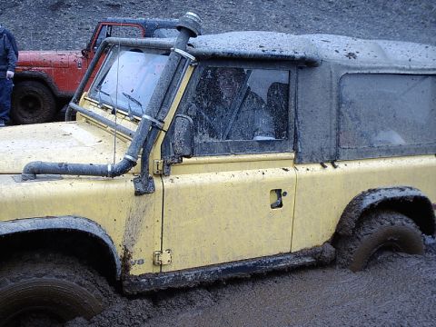 1996 Ford Bronco - A yellow off-road vehicle is stuck in thick mud, with another vehicle visible behind it.