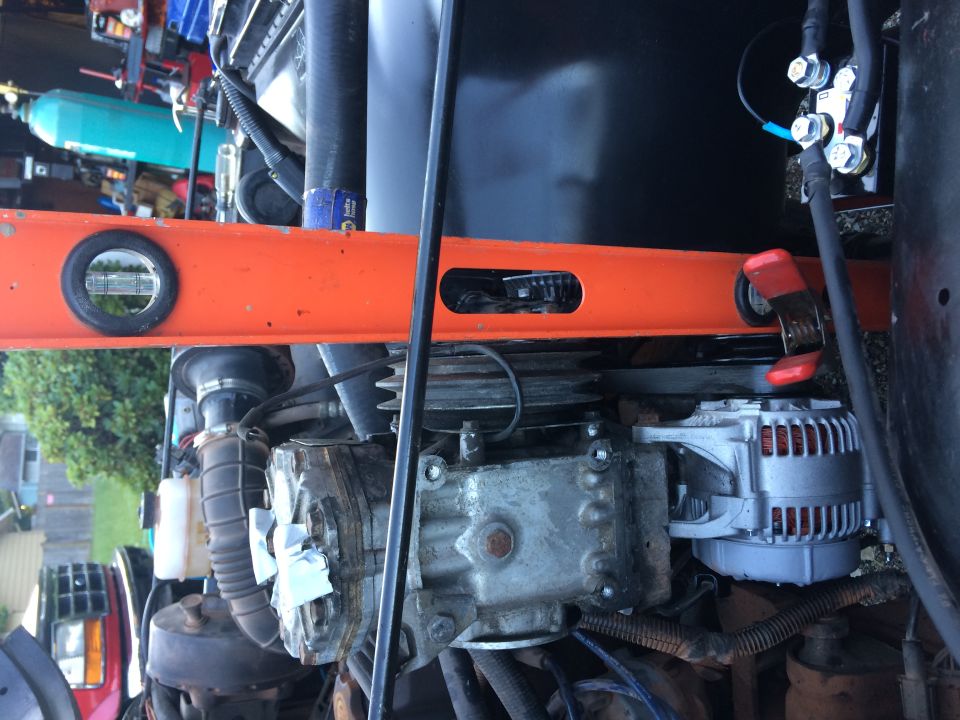 Engine bay with orange level tool over alternator and engine block.