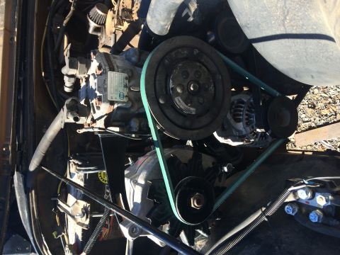 1995 Jeep Wrangler - A close-up view of the engine bay of a Jeep YJ, focusing on the air conditioning compressor and serpentine belt system.
