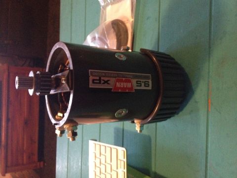 1995 Jeep Wrangler - A dark green Warn 9.5 XP winch motor is shown mounted on a teal wooden surface. The motor has a silver gear and shaft protruding from the l…