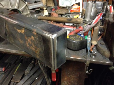 1995 Jeep Wrangler - A close-up view of a metal tube with rust spots, resting on a workbench cluttered with tools and supplies. The scene appears to be a worksh…