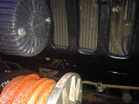 1995 Jeep Wrangler - A close-up view shows the front of a vehicle, focusing on a black winch drum with orange synthetic rope and a portion of the radiator and e…
