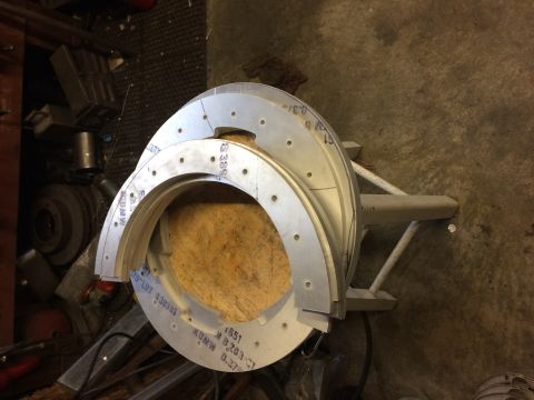 1995 Jeep Wrangler - Several circular metal rings with punched holes are stacked and resting on a wooden block. Some of the rings have text and numbers stamped…