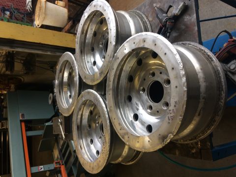 1995 Jeep Wrangler - A stack of five polished aluminum wheels are displayed in a workshop setting. The wheels appear to be for a Jeep YJ, with visible bolt patt…