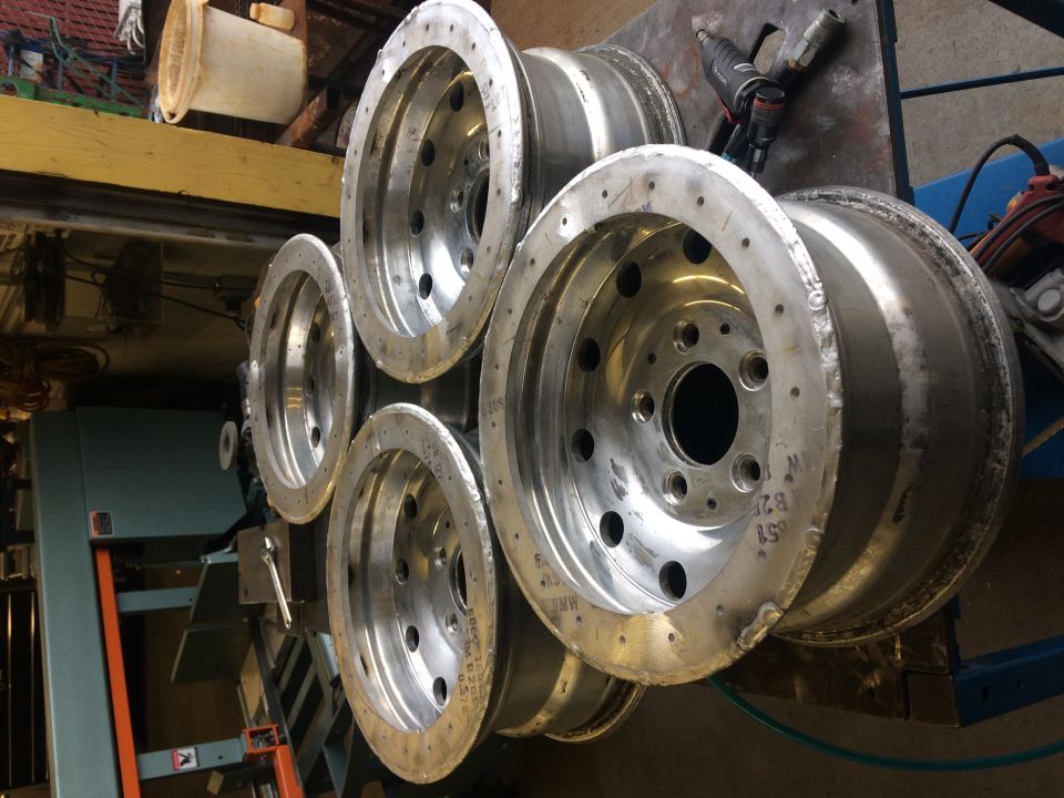 Stack of five polished aluminum Jeep YJ wheels in a workshop