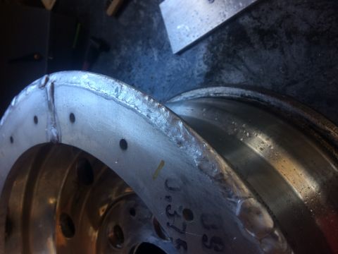 1995 Jeep Wrangler - A close-up, angled view shows the welded edge of a metal wheel, possibly from a Jeep YJ, with visible weld beads and several small bolt hol…