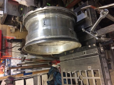 1995 Jeep Wrangler - A damaged aluminum wheel is clamped to a metal surface with a vise grip. The wheel has a crack marked with black ink and the word "Check".