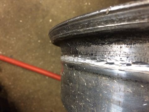 1995 Jeep Wrangler - A close-up, angled view of the damaged rim of a vehicle wheel. The metal shows significant chipping, cracking, and wear along the edge.