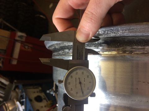 1995 Jeep Wrangler - A caliper is being used to measure the thickness of a metal wheel rim. The caliper is positioned to measure the outer edge of the rim.