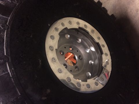 1995 Jeep Wrangler - A close-up view of a large, black tire with a custom beadlock wheel assembly attached. The wheel is silver with numerous bolts securing the…