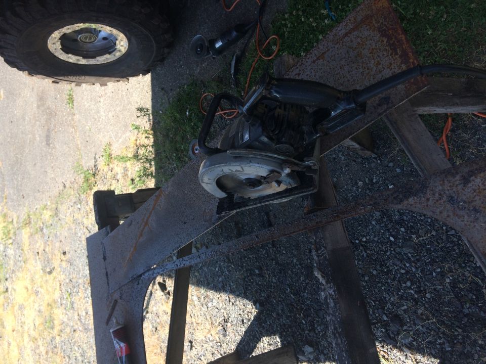 Circular saw on rusty metal frame with vehicle tire in background