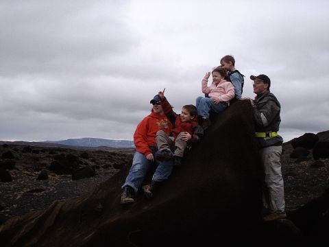 1996 Ford Bronco - A family enjoys a scenic view while perched atop a large rock in a desolate, rocky terrain.