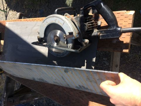 1995 Jeep Wrangler - A circular saw is positioned over a sheet of metal, with a hand holding the edge of the metal.