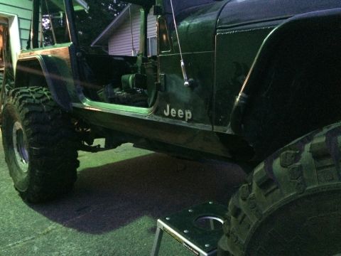 1995 Jeep Wrangler - A dark green Jeep YJ is shown from the side, with large off-road tires and the doors removed. The word "Jeep" is visible on the side panel.