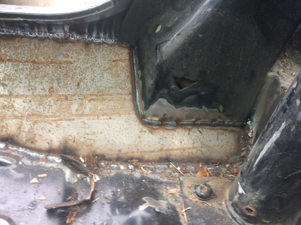 Close-up of welded metal on a vehicle's undercarriage, showing rust and grime.