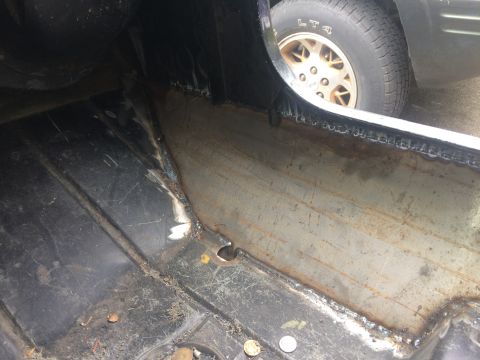 1995 Jeep Wrangler - Close-up of a modified Jeep rocker panel, showing rust and part of a wheel.