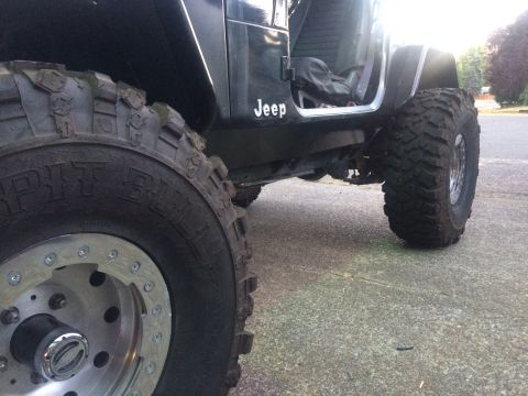 1995 Jeep Wrangler - Close-up of a 1995 Jeep YJ's side, highlighting its off-road tires and modified rocker panel.
