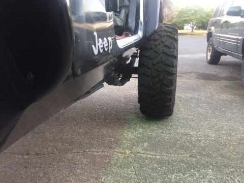1995 Jeep Wrangler - A Jeep with prominent "Jeep" lettering on its side is shown with a large off-road tire.