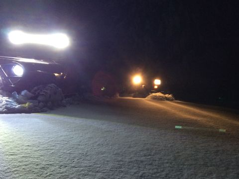 1995 Jeep Wrangler - Two vehicles are seen in a snowy landscape at night, illuminated by their headlights and auxiliary lights.