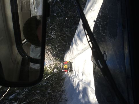 1995 Jeep Wrangler - A small yellow vehicle navigates a snow-covered trail, seen from the perspective of another vehicle.
