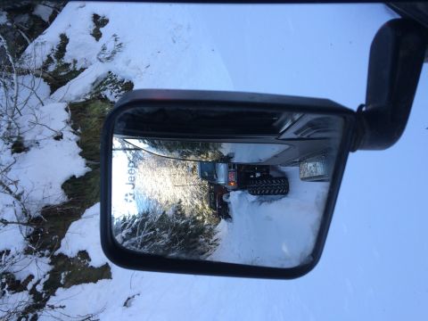 1995 Jeep Wrangler - Reflection shows a Jeep Wrangler with large tires driving in a snowy environment.