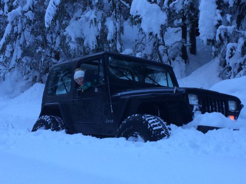 1995 Jeep Wrangler - A black 1995 Jeep YJ is partially buried in snow during a winter run, with a person visible in the driver's seat.