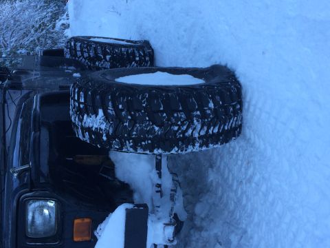 1995 Jeep Wrangler - A Jeep Wrangler is partially buried in snow, with two spare tires visible on its side.