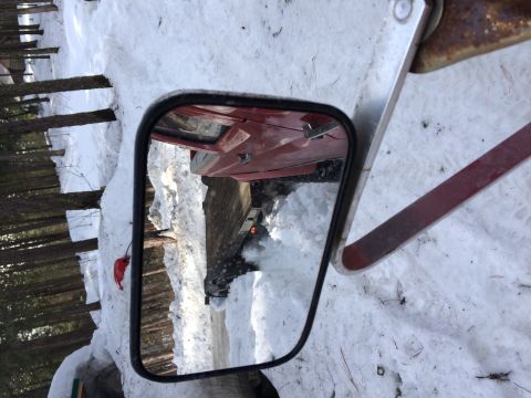 1995 Jeep Wrangler - Reflection in the side mirror shows a red vehicle in a snowy environment.