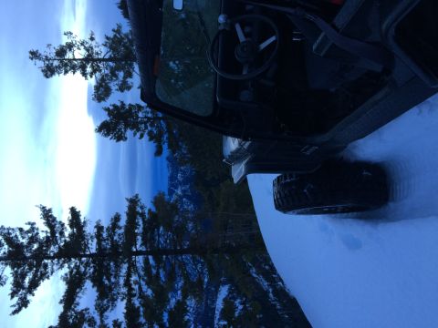 1995 Jeep Wrangler - A Jeep Wrangler sits in the snow, facing a winter landscape with trees and mountains.