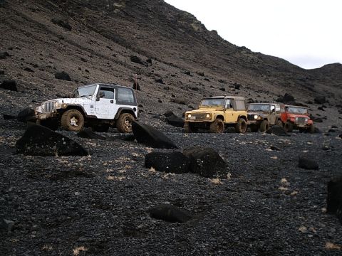 1996 Ford Bronco - Multiple off-road vehicles navigate a challenging, rocky terrain under an overcast sky.